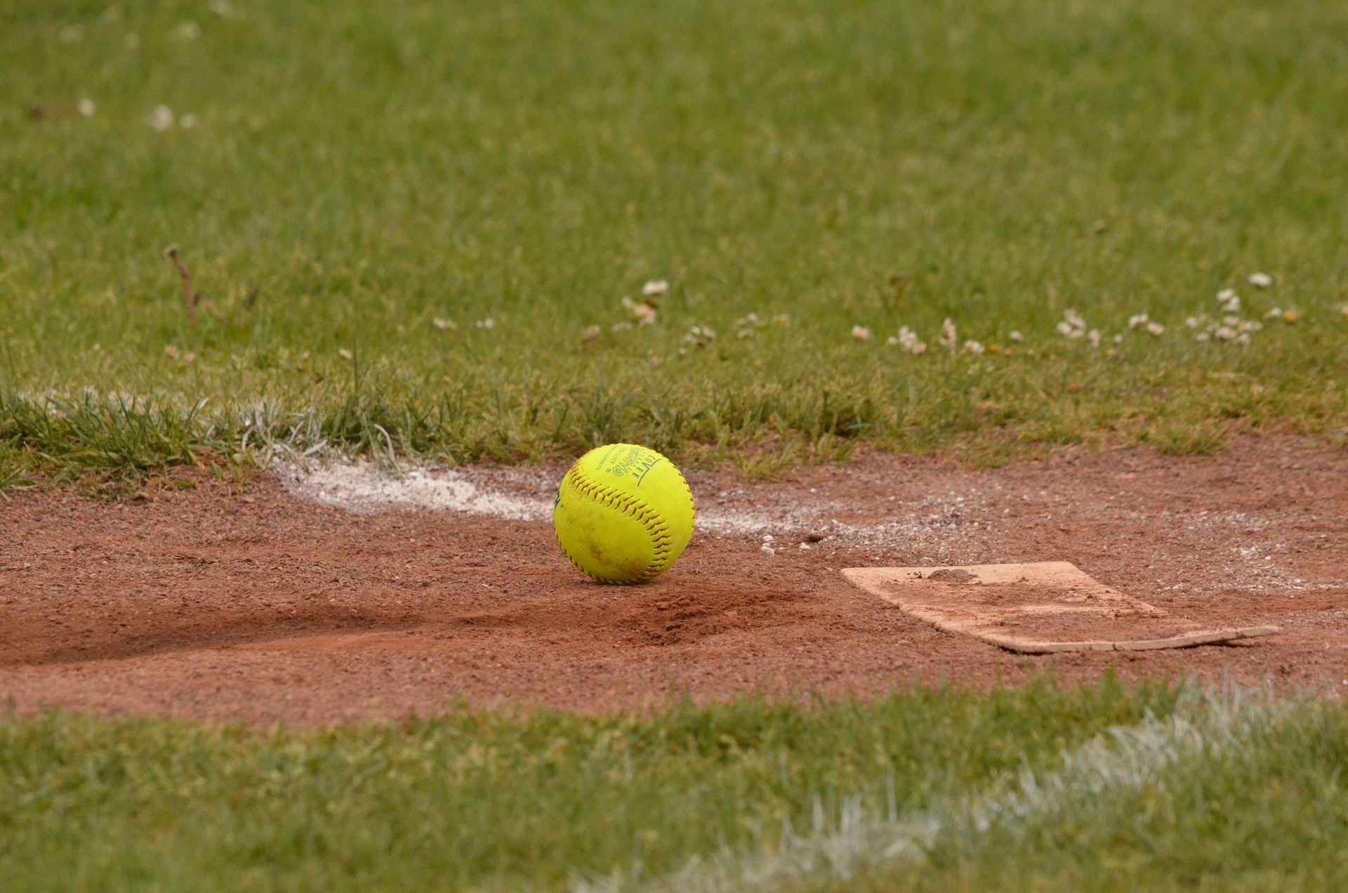 Softball on plate in dirt surrounded by grass